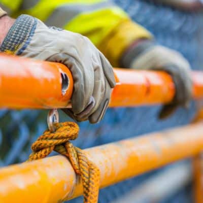 gloved hands leaning on an orange pipe